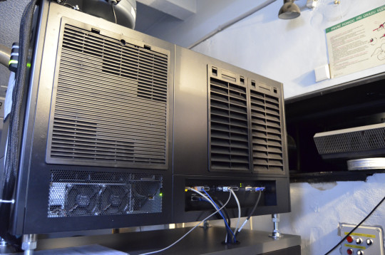 31. Digitální projektor z bočního pohledu. Vpravo dole se nachází komunikační rozhraní, vlevo nahoře je ventilační mřížka lampové skříně